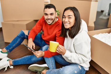 Genç Latin çift kahve içiyor ve yeni evlerinde dokunmatik ped kullanıyor..