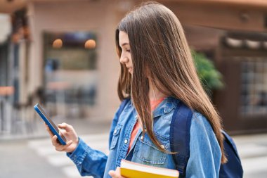 Adorable girl student using smartphone at street