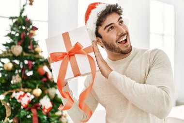 Genç İspanyol adam gülümsüyor. Mutlu bir hediye tutuyor..