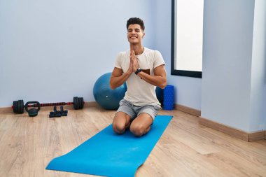 Spor merkezinde yoga eğitimi alırken gülümseyen İspanyol genç adam.