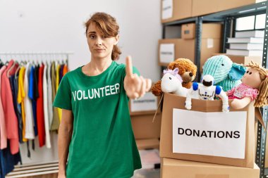 Beautiful caucasian woman wearing volunteer t shirt at donations stand pointing with finger up and angry expression, showing no gesture 
