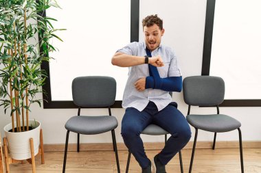 Yakışıklı genç adam, kolundan yaralanmış bir şekilde bekleme odasında oturuyor. Saatine bakıyor. Endişeli, geç kalmaktan korkuyor. 