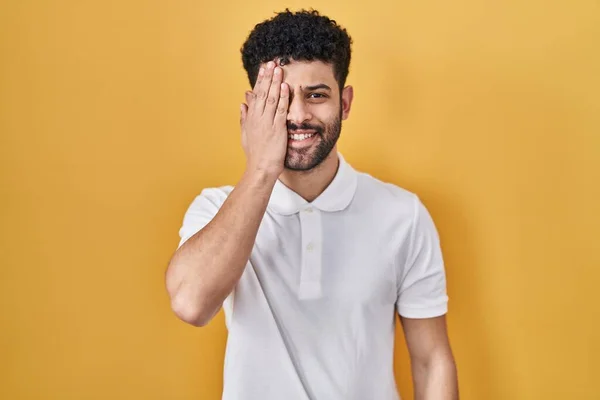 Homem Árabe Sobre Fundo Amarelo Cobrindo Olho Com Mão Sorriso — Fotografia de Stock