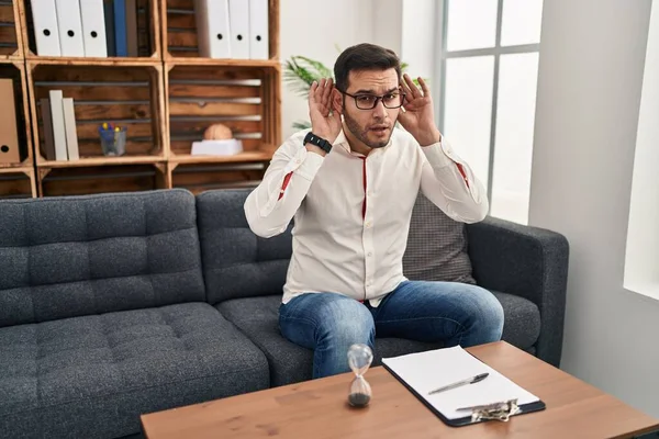 Young Hispanic Man Beard Working Consultation Office Trying Hear Both — Fotografia de Stock