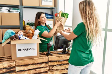İki gönüllü kadın, hayır kurumunda çalışmaktan mutlu gülümsüyor..
