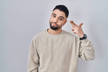 Genç yakışıklı adam izole edilmiş arka planda duruyor ve kendini vuruyor. Elini ve parmaklarını silah gibi kullanıyor. İntihar jesti.. 