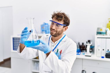 Laboratuvarda deney tüpü tutan bilim adamı üniforması giyen İspanyol genç adam.