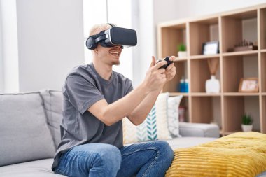 Young caucasian man playing video game using virtual reality glasses at home