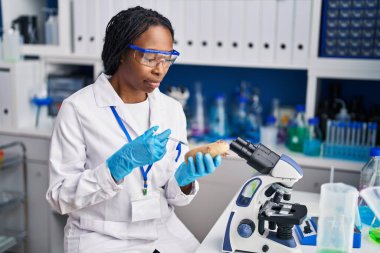 African american woman wearing scientist injecting on potato laboratory