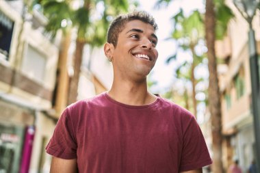 Genç Latin adam gülümseyerek şehirde mutlu mesut dikiliyor..