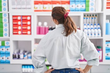 Young woman customer standing on back view at pharmacy