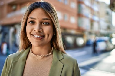 Sokakta kendinden emin gülümseyen genç Latin kadın.