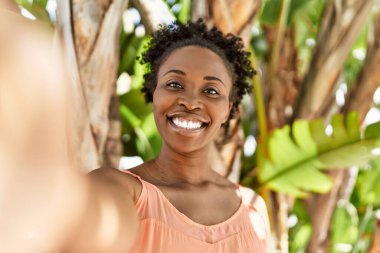 Genç Afrikalı Amerikalı bir kadın bir yaz günü mutlu bir şekilde gülümseyip selfie çekiyor.