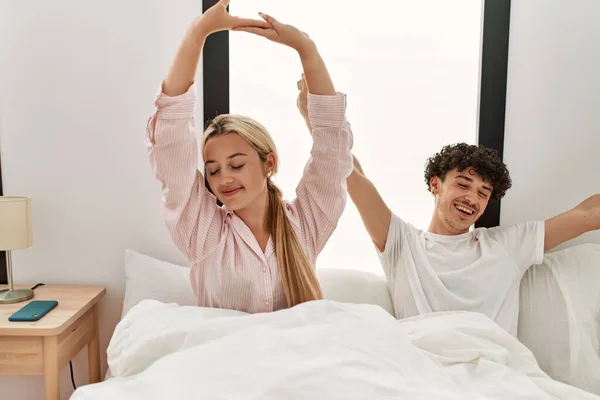 Jovem Casal Bonito Bocejando Esticando Braços Sentados Cama — Fotografia de Stock