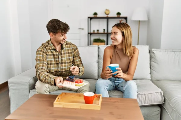 Jovem Casal Hispânico Sorrindo Feliz Tomando Café Manhã Sentado Sofá — Fotografia de Stock