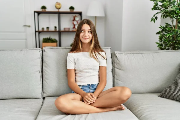 Young Brunette Teenager Sitting Sofa Home Smiling Looking Side Staring — Stock fotografie