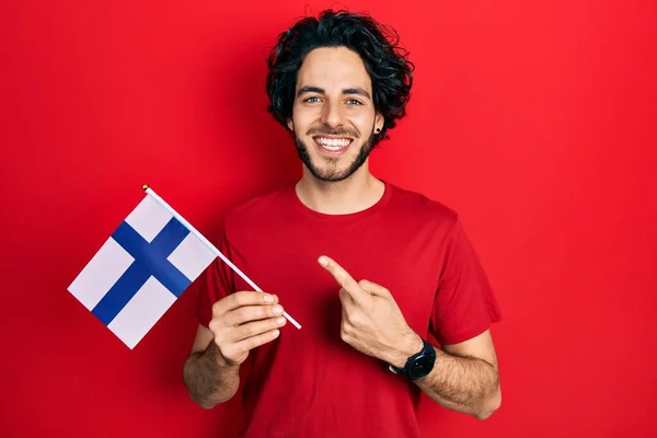 Snygg Latinamerikansk Man Med Finländsk Flagga Som Ler Glad Pekar — Stockfoto