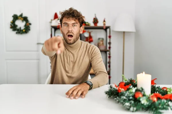 Mladý Pohledný Muž Vousy Sedící Stole Vánoční Výzdoby Ukazuje Nespokojeně — Stock fotografie
