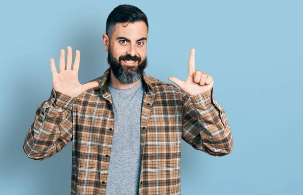 自信と幸せ笑顔ながら髭を生やしたヒスパニック系の男はカジュアルなシャツを着て表示され 指番号7で指摘します — ストック写真