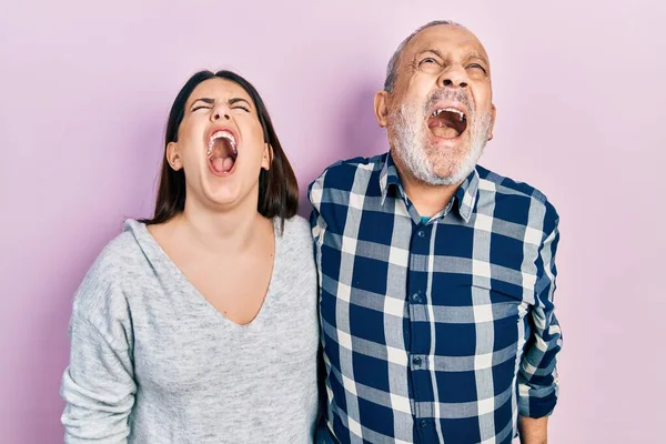 Hispanic father and daughter wearing casual clothes angry and mad screaming frustrated and furious, shouting with anger. rage and aggressive concept.