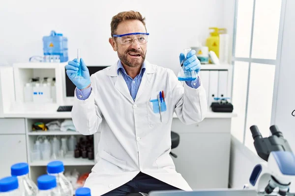 Мужчина Средних Лет Работающий Научной Лаборатории Держит Химические Продукты Подмигивая — стоковое фото