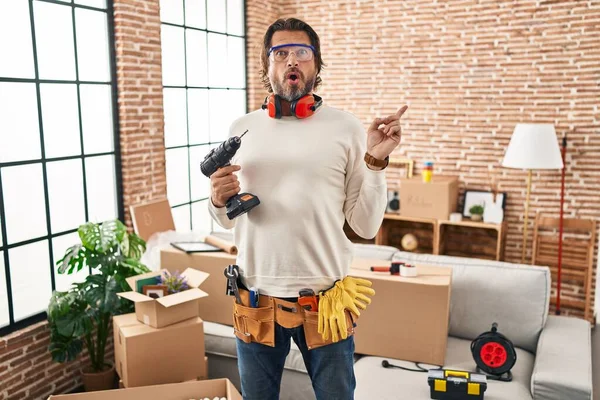Handsome Middle Age Man Holding Screwdriver New Home Surprised Pointing — Stockfoto