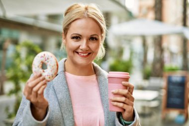 Sarışın genç iş kadını şehirde kahvaltı yapıyor..