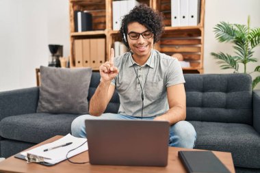 Kıvırcık saçlı İspanyol bir adam danışma ofisinde bir fikir ya da soru işareti ile gülümsüyor. 