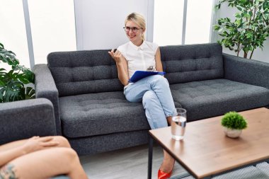 Young psychologist woman at consultation office beckoning come here gesture with hand inviting welcoming happy and smiling 