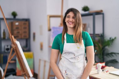 Sanat stüdyosundaki genç esmer kadın yan bakmak için, rahat profil pozu doğal bir yüz ve kendinden emin bir gülümseme ile. 