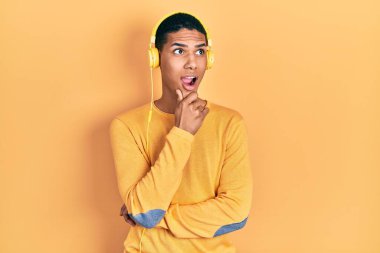 Genç Afro-Amerikalı adam kulaklık takıp müzik dinliyor. Bir soru hakkında endişeli ve gergin. 