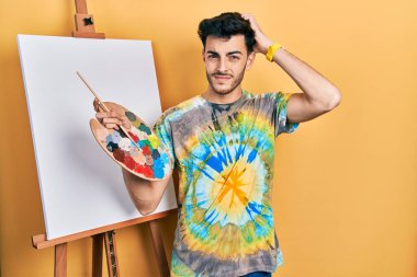 Genç İspanyol bir adam boyacı sehpasında paletle resim çiziyor. Kafası karışıyor ve soru soruyor. Şüpheyle kararsız, kafa kafaya düşünerek. Düşünceli kavram. 