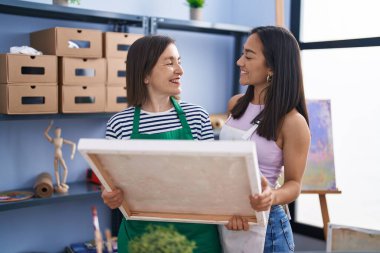 Two women artists standing together holding draw at art studio