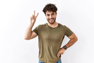 Hispanic man standing over isolated white background smiling looking to the camera showing fingers doing victory sign. number two. 