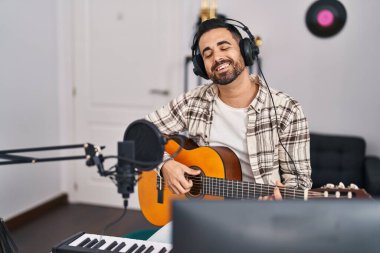 Genç İspanyol sanatçı müzik stüdyosunda gitar çalarak şarkı söylüyor.