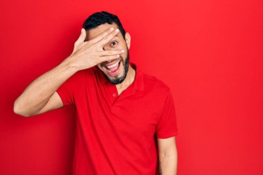 Sakallı, sıradan kırmızı tişörtlü İspanyol bir adam. Şoka girmiş, yüzünü ve gözlerini kapamış, utangaç ifadesiyle parmaklarının arasından bakıyor.. 