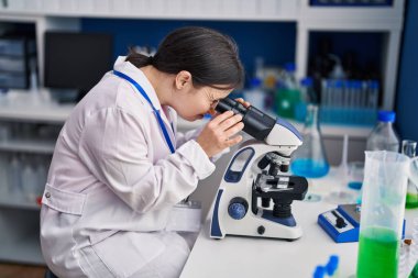 Young woman with down syndrome scientist using microscope at laboratory