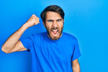 Latin asıllı genç bir adam, kızgın ve kızgın. Öfkeyle bağırırken yumruğunu sallıyor ve öfkeleniyor. öfke ve agresif konsept. 