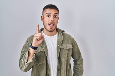 Tecrit edilmiş arka planda duran genç bir İspanyol başarılı bir fikir işaret ediyor. Heyecanlı ve mutlu. Bir numara.. 