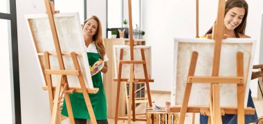 Anne ve kızı resim stüdyosunda kendine güvenen bir şekilde gülümsüyor.