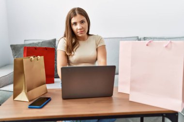 Genç İspanyol kadın evde laptop alışverişi yapıyor.