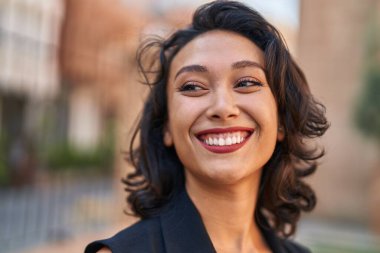 Young beautiful hispanic woman smiling confident looking to the side at street