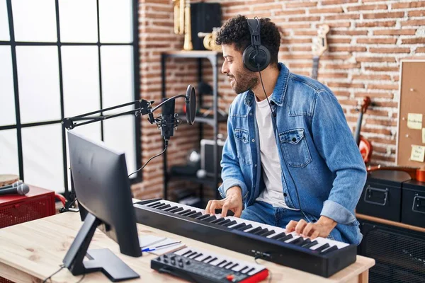 Genç Arap müzisyen müzik stüdyosunda piyano klavyesi çalıyor.