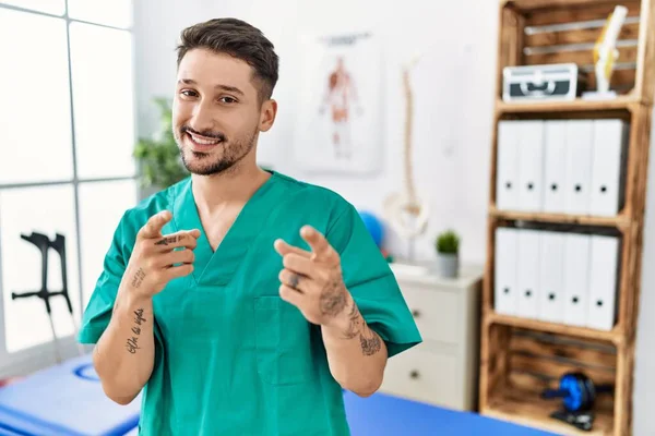 Young Physiotherapist Man Working Pain Recovery Clinic Pointing Fingers Camera — Stockfoto
