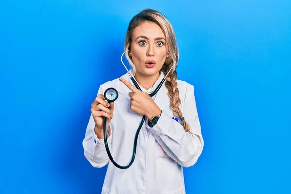 Beautiful Young Blonde Doctor Woman Holding Stethoscope Surprised Pointing Finger — Stok fotoğraf