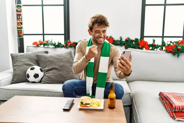 Młody Hiszpan Wspierający Mecz Piłki Nożnej Przy Użyciu Smartfona Siedzącego — Zdjęcie stockowe