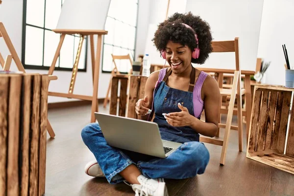 在艺术工作室使用笔记本电脑和耳机的年轻非洲裔美国妇女 — 图库照片