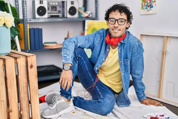 Young Hispanic Man Artist Wearing Headphones Sitting Floor Art Studio — Stockfoto