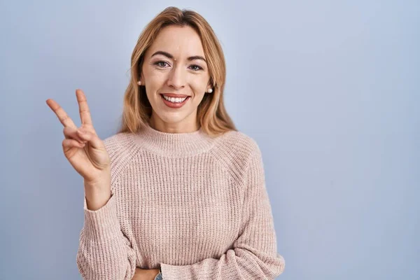 Mujer Hispana Pie Sobre Fondo Azul Sonriendo Mirando Cámara Mostrando —  Fotos de Stock