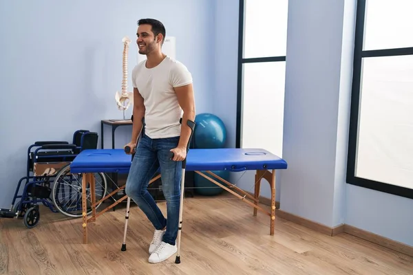 Young Hispanic Man Injured Physiotherapy Patient Using Crutches Walking Rehab — Stockfoto